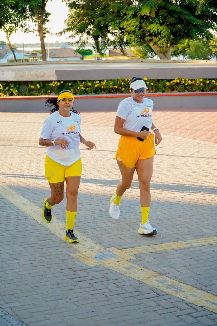 Two women jogging in colorful attire during a sunny day outdoors.