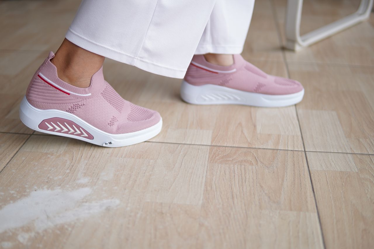 Close-up of pink slip-on sneakers on a tile floor, highlighting fashion and comfort.