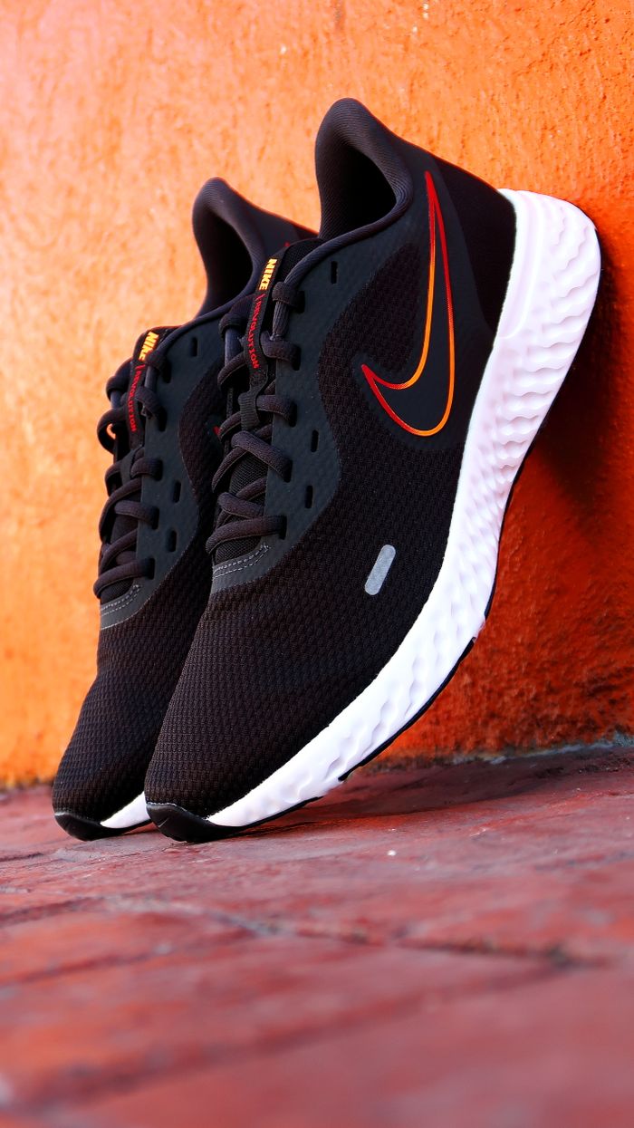 The Art of Drawing Readers In: Your attractive post title goes here Close-up of black running shoes with orange swoosh against an orange wall.